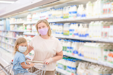 Portrait of a mother and her little daughter wearing protective face mask at a supermarket during the coronavirus epidemic or flu outbreak. Empty space for text