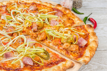 Meat pizza with sliced slice on a wooden board