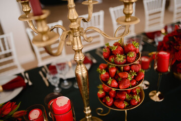 Beautiful strawberries served in the restaurant on the table next to the golden candlestick