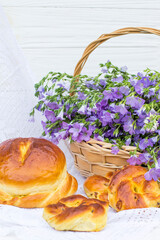 Delicious pastries (bread and rolls with raisins) and bouquet linen in wicker basket