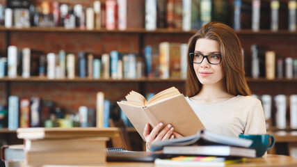 Attractive young girl student with lots of books in a cafe