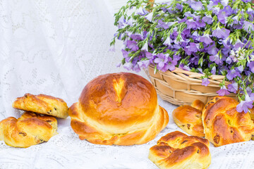 Delicious pastries (bread and rolls with raisins) and bouquet linen in wicker basket