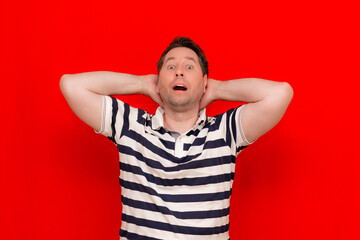 Fototapeta premium Dreamy european man wearing striped t-shirt standing relaxing and stretching, arms and hands behind head