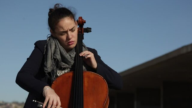 Mujer tocando con pasi&oacute;n el violonchelo durante un concierto.