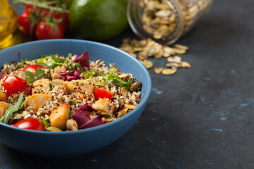 Salad with quinoa, avocado and chicken. Front view. Served in a blue bowl.