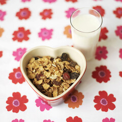 Muesli in heart bowl with a glass of milk