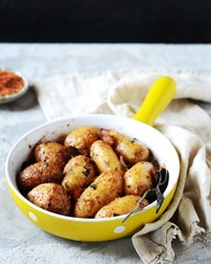 Baked young potatoes with bacon on a gray background, still life
