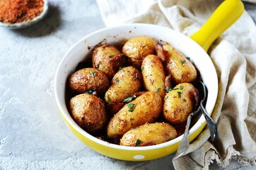 Baked young potatoes with bacon on a gray background, still life