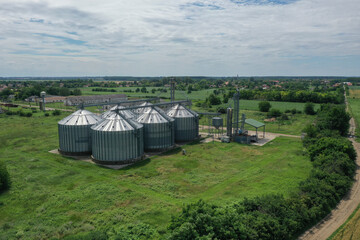 Fototapeta na wymiar Agricultural silos on a farm, photos from above with a drone. Industrial agricultural granary, processing plant, elevator dryer, storage and drying of cereals, wheat, corn, soybeans, sunflowers.