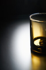 Vertical photo of empty glass on a matte black background with backlight
