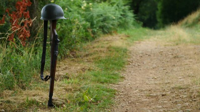 Memorial battlefield cross. Symbol of a fallen US soldier. M1 rifle with helmet.