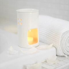 Oil burner and rolled-up towel beside the bathtub