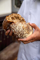 Baker holding fresh bread. He broke it in half.