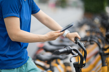 People using smartphone scanning the QR code of shared bike in city