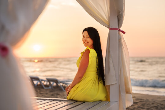 Girl in a yellow dress meets dawn on the seashore