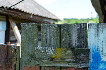 Old wooden fence in a rustic style close-up, painted in different colors and occupying the bottom of the frame.