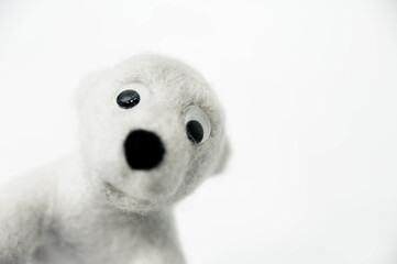 toy polar bear made of felted wool looking out of the corner of the frame on white background