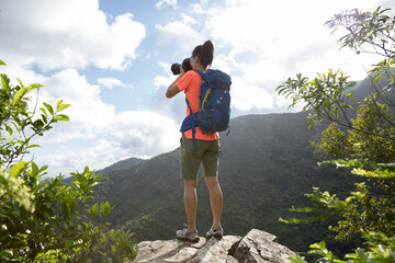 Woman photographer taking pictures on top of summer mountains