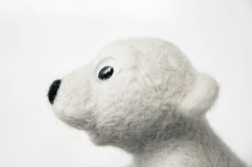 profile portrait of toy polar bear made of felted wool on white background