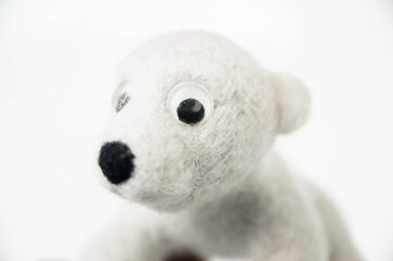 toy polar bear made of felted wool looking at you from the white background