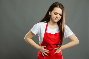Portrait of female supermarket employee holding stomach like hurting