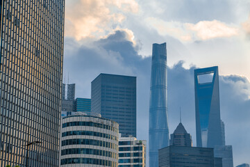 The modern skyscrapers in Lujiazui, the financial district in Shanghai, China, shot at sunset, on a cloudy day.