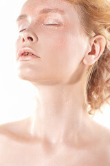 Shining creative makeup in bright colors. Closeup portrait of a young blonde with radiant make-up with highlighter.