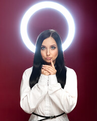 Dark-haired girl on a red background with a halo from a ring lamp