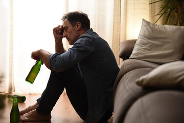 Sad man sitting in the living room drinking alcohol