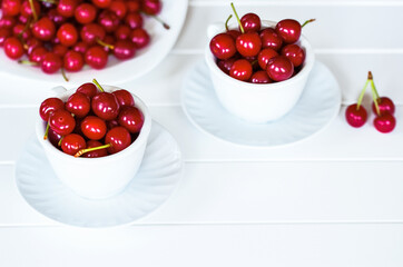 ripe fresh cherries on a white background close-up. background with cherries in white bowls.