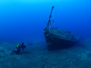 scuba divers exploring ship wreck underwater ocean scenery photography 