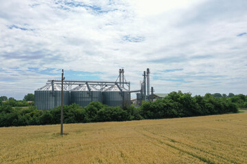 Fototapeta premium Agricultural silos on a farm, photos from above with a drone. Industrial agricultural granary, processing plant, elevator dryer, storage and drying of cereals, wheat, corn, soybeans, sunflowers.