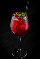Cold sangria wine in a wine glass with reflection on black background