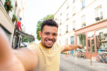 Fototapeta premium smiling young african american mixed race man taking selfie on city street and pointing