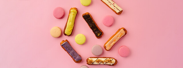 Top view of eclair cakes and macaroon cookies on pink backgfround