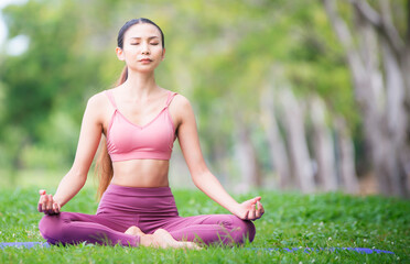 Asian model poses yoga in a park on a natural green background, health care concept, beautiful body structure, fit body