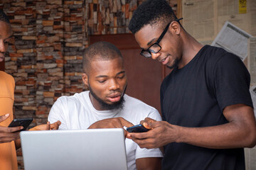 three african people, men, using mobile phones and laptop computer, sharing ideas © Confidence