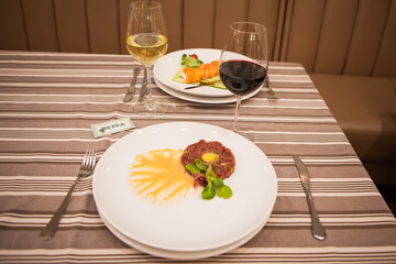 Served delicious food in the restaurant, salads, dishes, meat, sauces. A glass of red wine, a glass of white wine.

