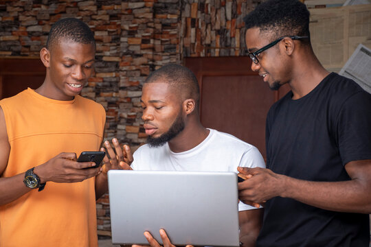 Three African People, Men, Using Mobile Phones And Laptop Computer, Discussing And Sharing Ideas