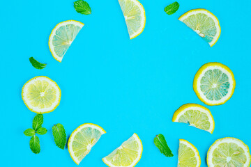 Lemon slices and mint leaves on blue pastel table top view. Ingredients for summer lemonade and cocktail. Flat lay.