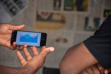two young people viewing a graph on a mobile phone , contemplating ideas, planning
