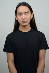 Young Asian man with long hair looking at camera