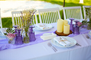 Elegant table setting for wedding engagement Easter dinner with white ceramic plates cotton napkin tied with twine lavender flowers candles. Provence style