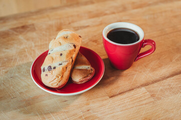 Cup of black coffee and croissant on a wooden board