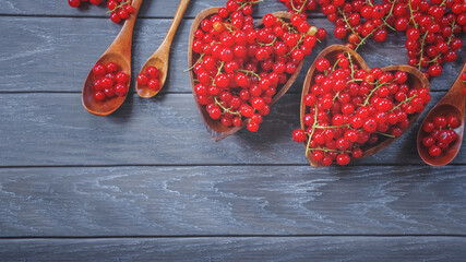 ripe currant berries in wooden bowls and wooden spoons on the table close-up. background with red currant berries. currant top view.