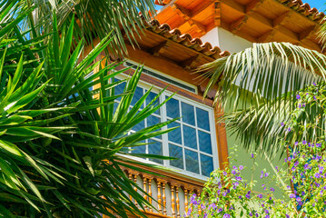 Fototapeta na wymiar Wooden window of a house with palm leaves and flowers, Puerto de la Cruz, Tenerife, Spain