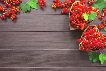 ripe currant berries in wooden bowls on a wooden background top view. currant and green currant leaves on a wooden background. currant and copy space.