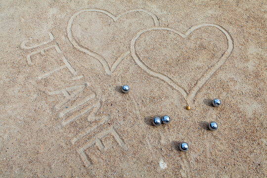 Bocce balls in sand with hearts