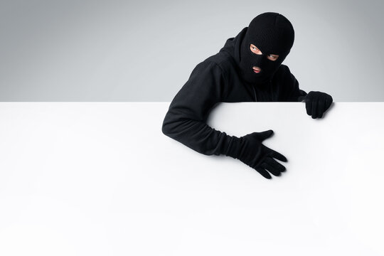 Masked thief holding white blank advertising board