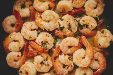 Baby shrimps with parsley and garlic are cooked in a pan, top view, flat lay, close-up